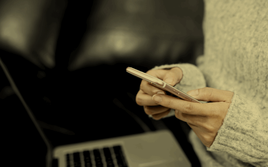 Hands holding a smartphone in a dimly lit setting, suggesting the need for digital connectivity and access to information.