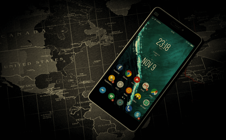 A smartphone displays the current date and time, resting on a dark, detailed map of the world, indicating the use of technology for global connectivity and information access.