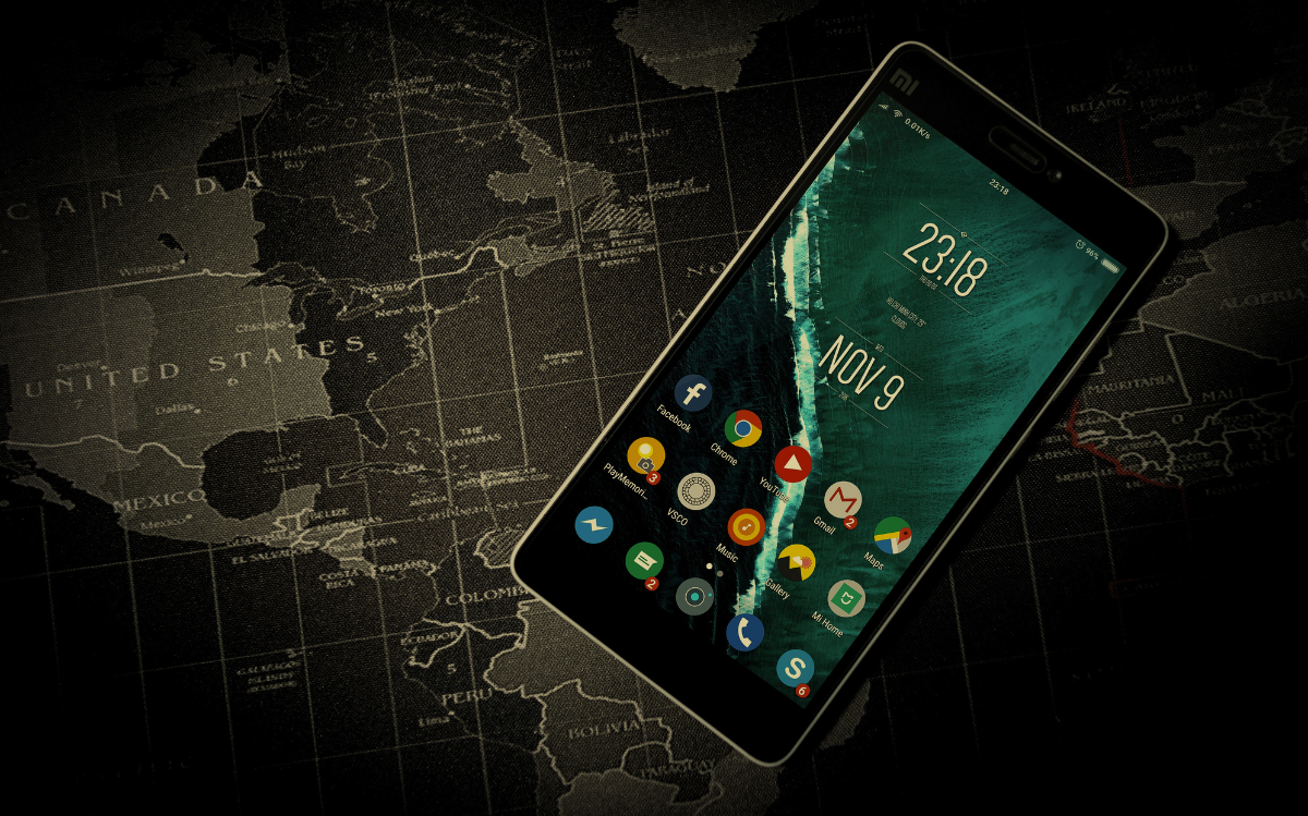 A smartphone displays the current date and time, resting on a dark, detailed map of the world, indicating the use of technology for global connectivity and information access.
