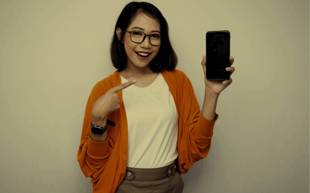 A smiling woman holding a smartphone, suggesting the accessibility of free government phones to stay connected.