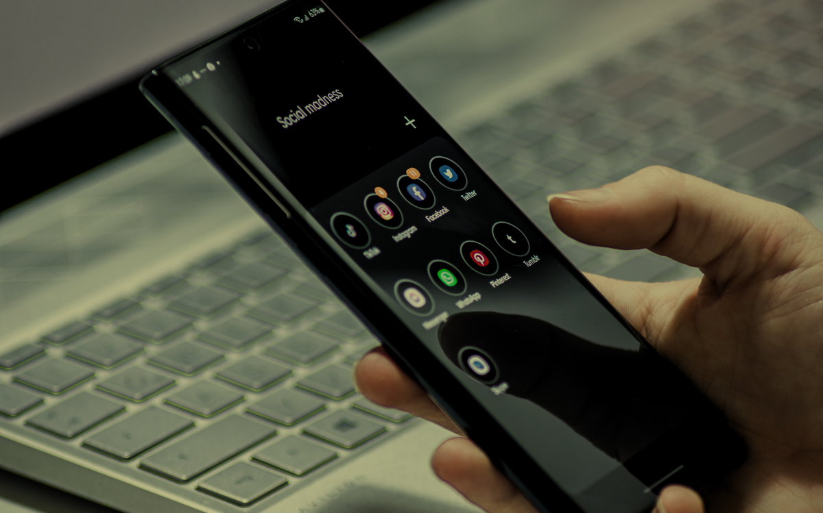 A person's hands holding a smartphone displaying various social media app icons, suggesting the importance of digital connectivity.