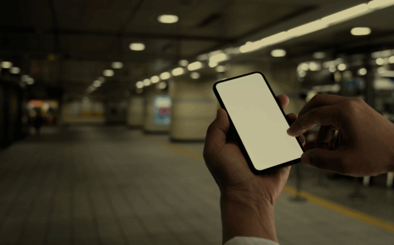 A hand is holding a mobile device in a blurred setting, hinting at the potential use of the phone for accessing programs or applications.